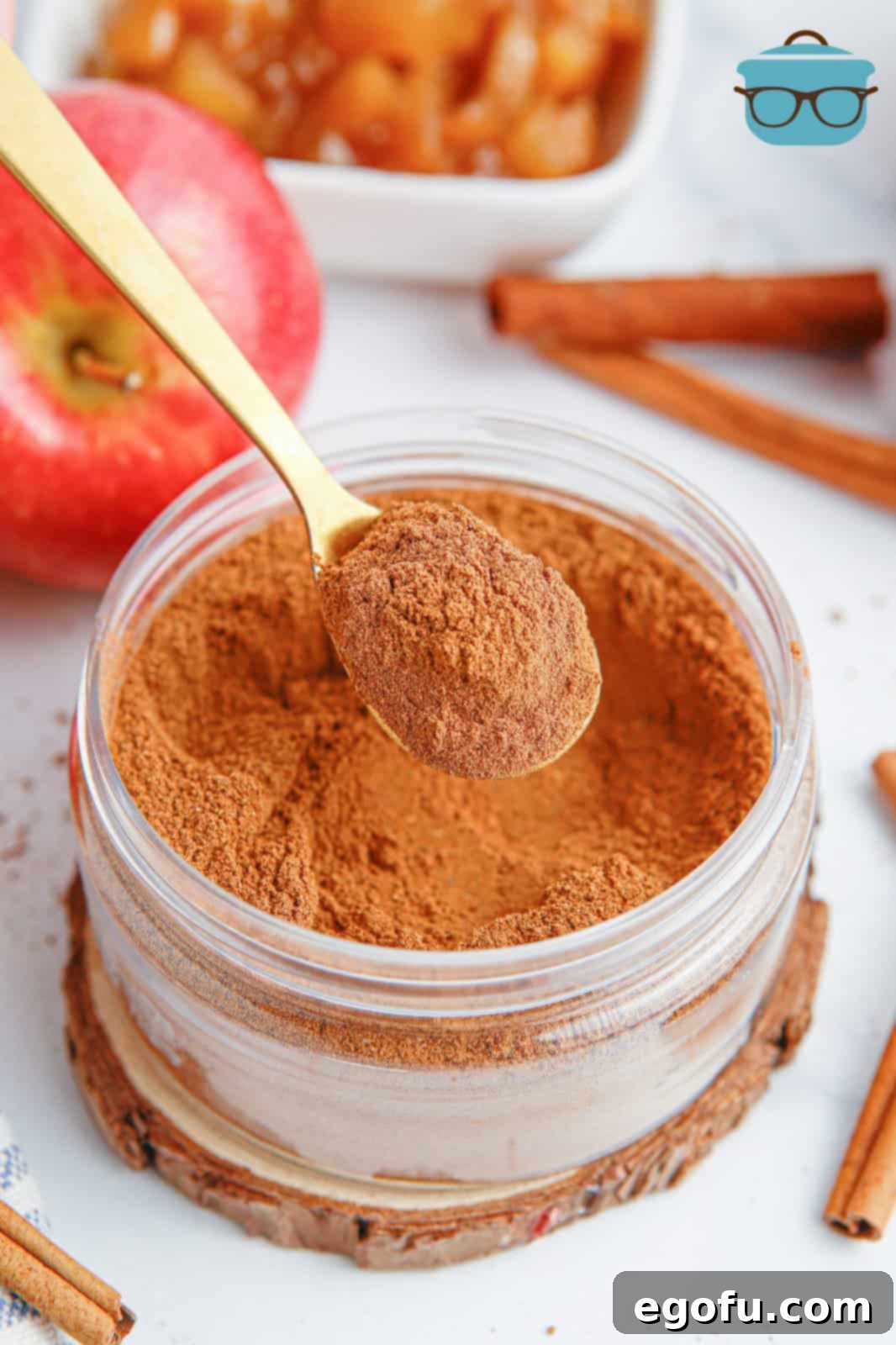 A spoon holding some Apple Pie Spice over the jar, showcasing the rich, brown blend of spices.