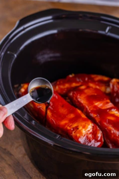 Tender Slow Cooker BBQ Country Style Ribs 14 Liquid smoke being poured in the crockpot with country style ribs.