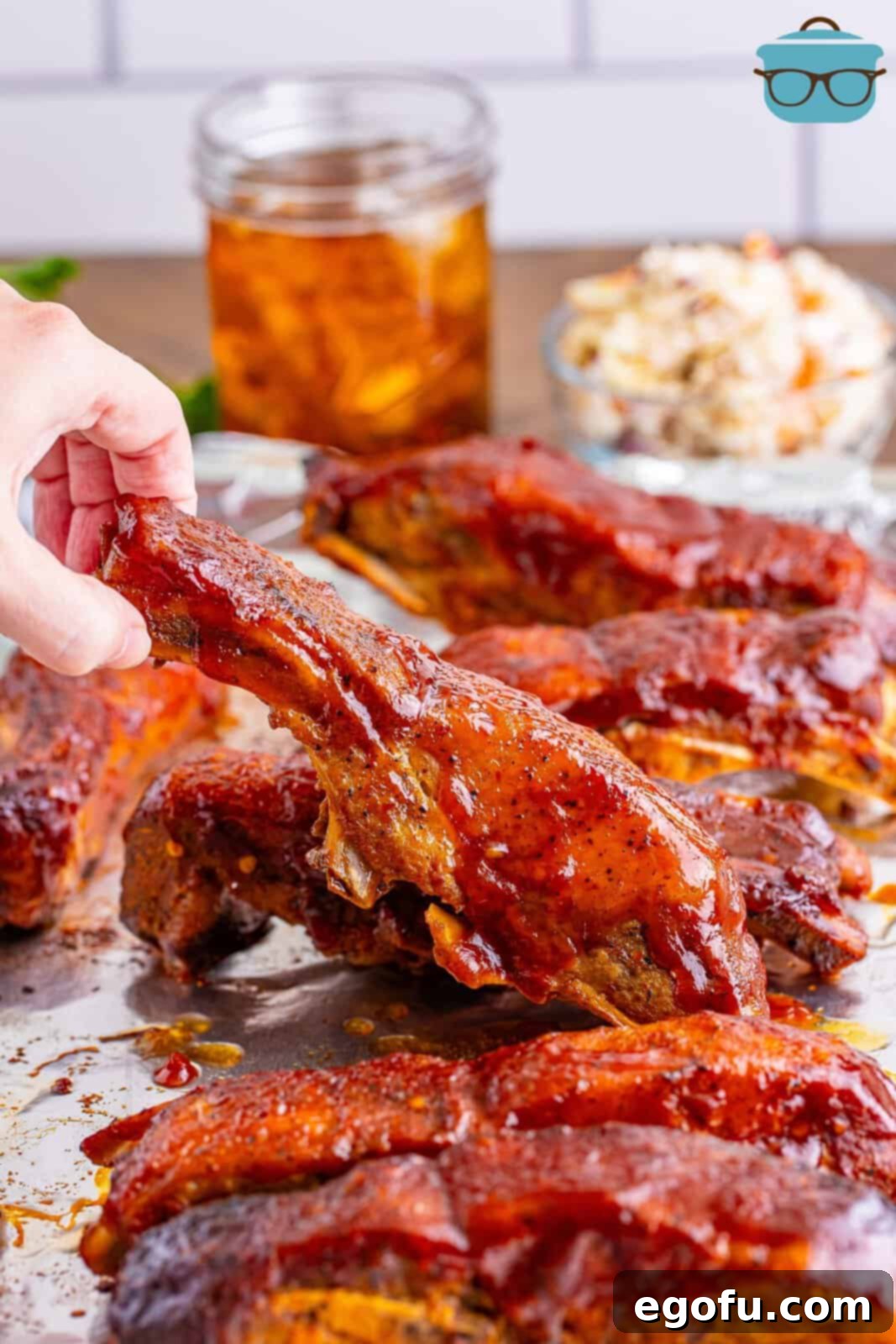 Tender Slow Cooker BBQ Country Style Ribs 8 A hand picking up one of the BBQ Country Style Ribs made in the Crock Pot.