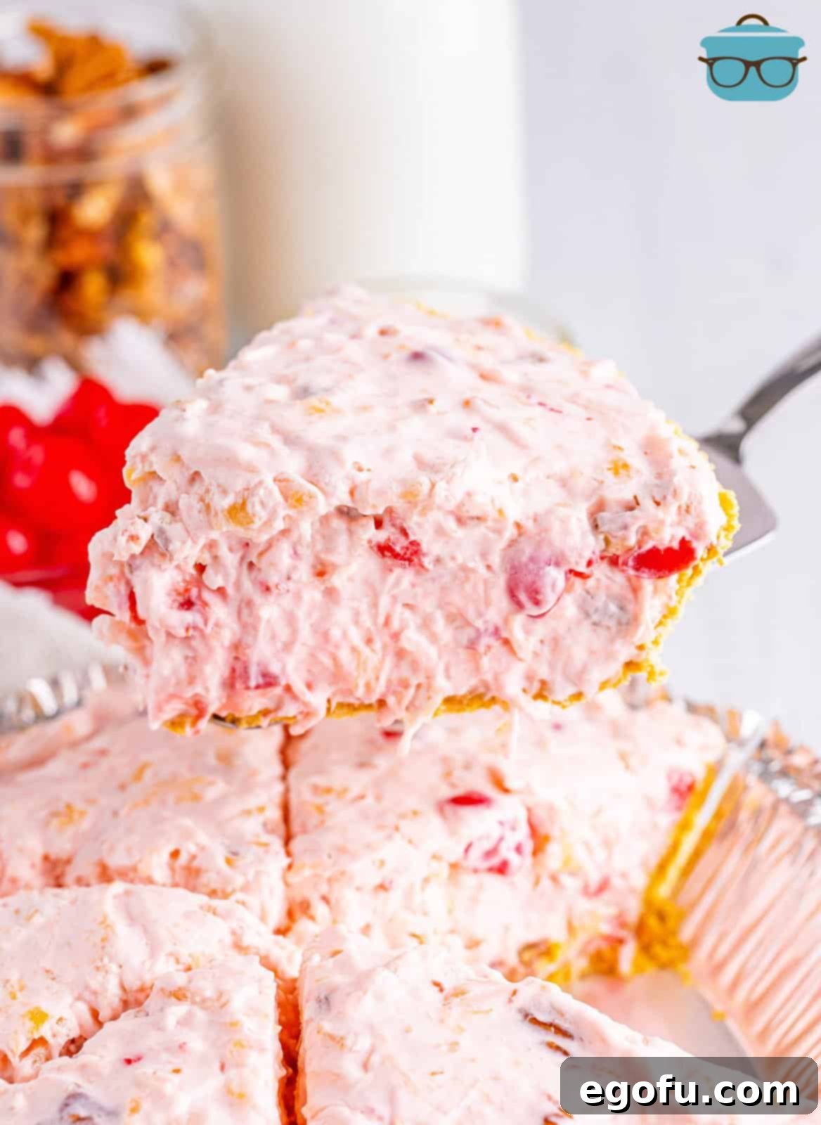 A close-up shot of a fork holding a perfect bite of Millionaire Pie, rich with pineapple, cherry, and coconut, positioned above the remaining slices of the beautifully set pie.