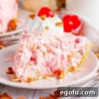 A small dessert plate with a perfectly cut piece of Millionaire Pie, topped with a cherry, ready to be enjoyed.