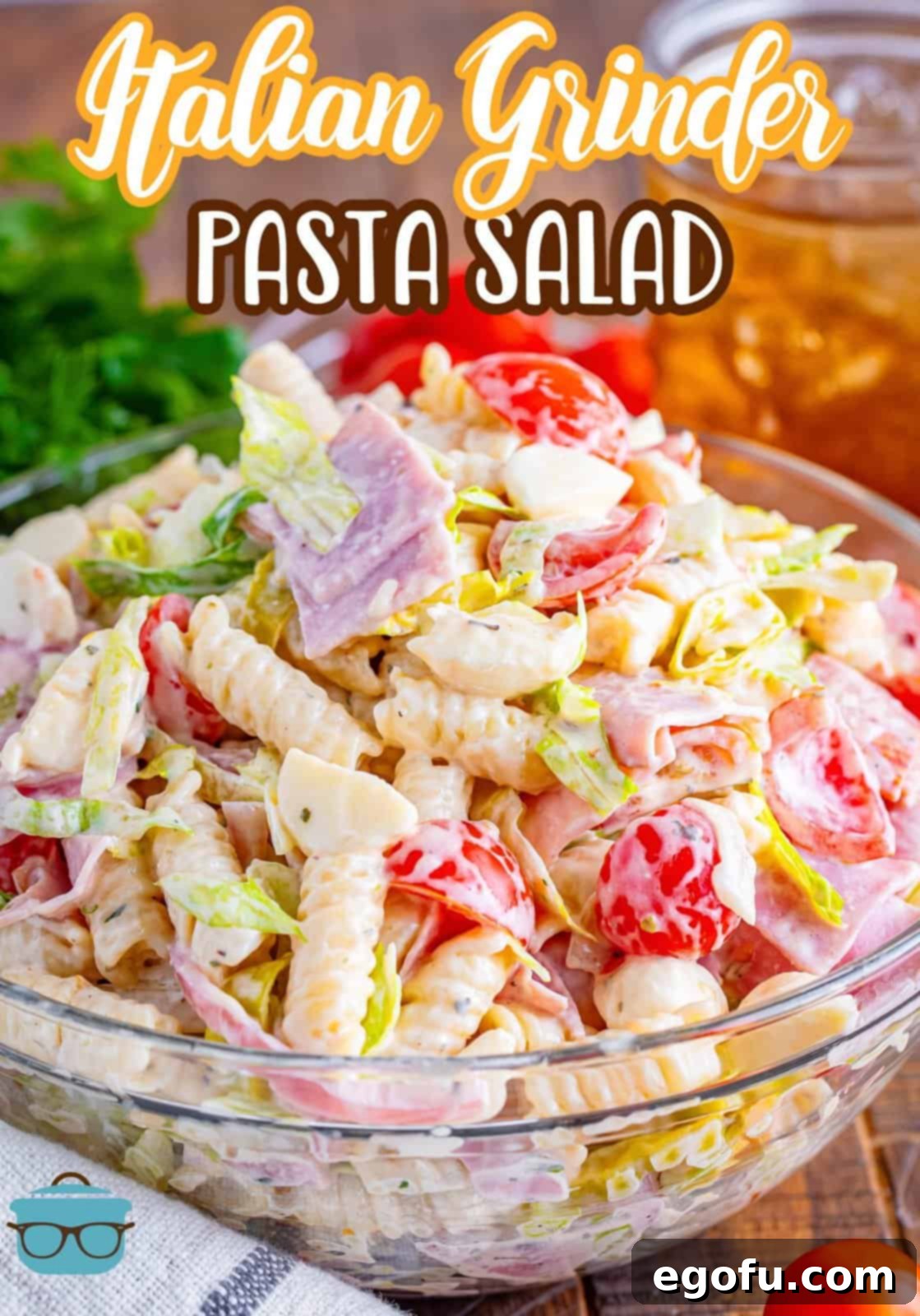 A heaping mounds of Italian grinder pasta salad and a glass mixing bowl.
