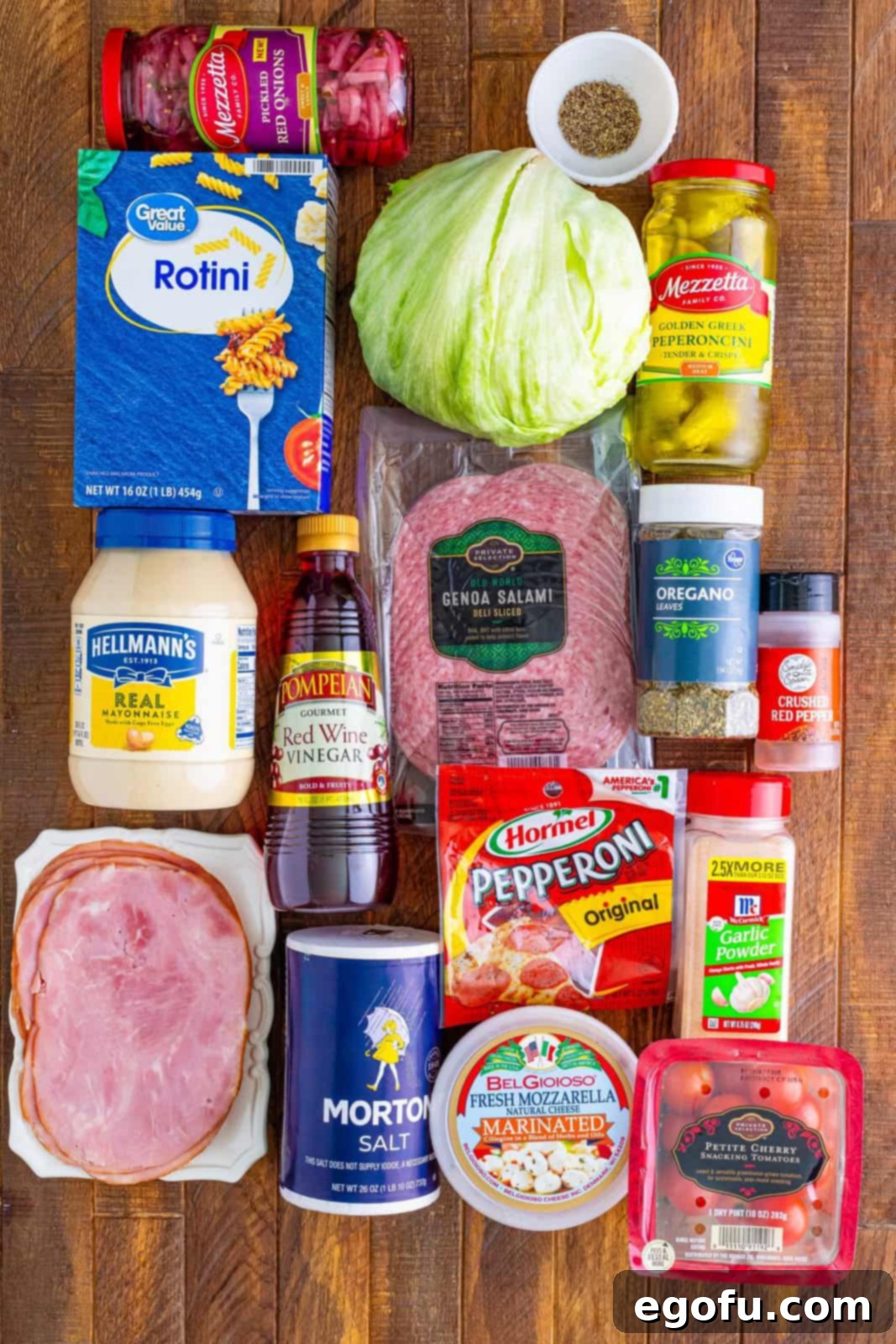 A head of lettuce, mayo, rotini, salt, pepper, red wine vinegar, deli ham, salami, pepperocini with juice, mozzarella  balls with juice, oregano, garlic powder, red pepper flakes, cherry tomatoes and pickled red onions.