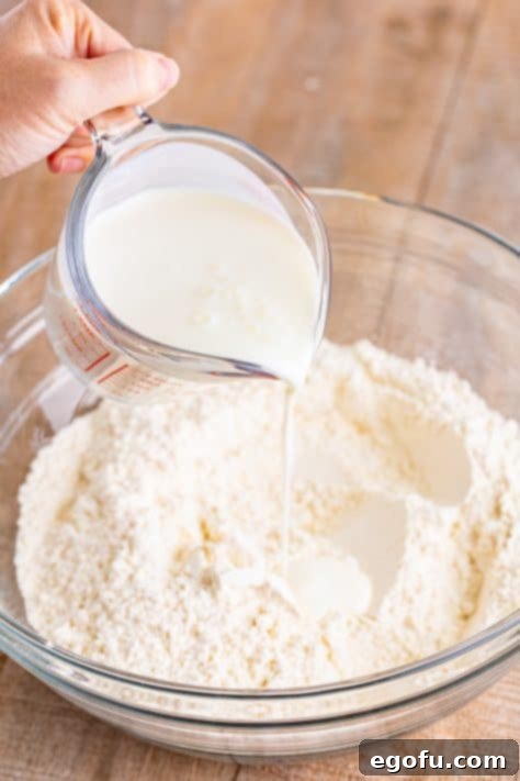 Buttermilk being poured in the dry ingredients in a mixing bowl.