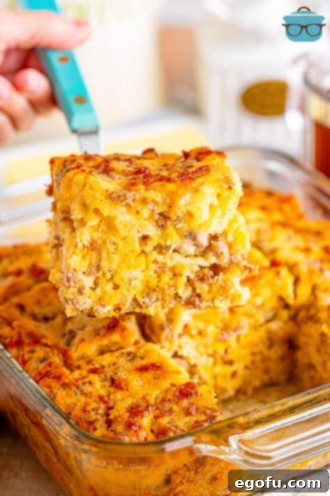 Serving utensil holding a breakfast butter swim biscuit above a baking dish.