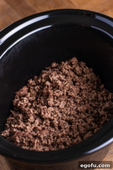 Copycat Wendy's Slow Cooker Chili 10 A slow cooker insert filled with ground beef.