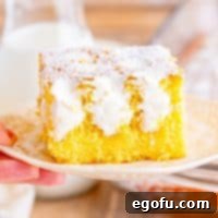 A slice of homemade Twinkie Poke Cake on a white plate, highlighting the yellow cake and marshmallow filling.