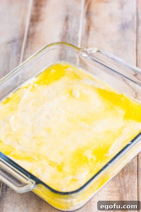 Garlic Butter Bath Biscuits 13 Melted butter in a baking dish with biscuit batter on top.