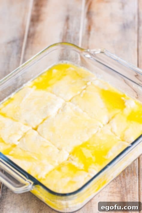 Garlic Butter Bath Biscuits 14 Melted butter with biscuit dough in a baking dish, scored into 9 sections.