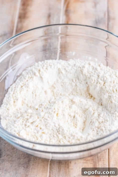 Garlic Butter Bath Biscuits 10 A glass mixing bowl with all-purpose flour, granulated sugar, aluminum-free baking powder, salt and garlic powder.
