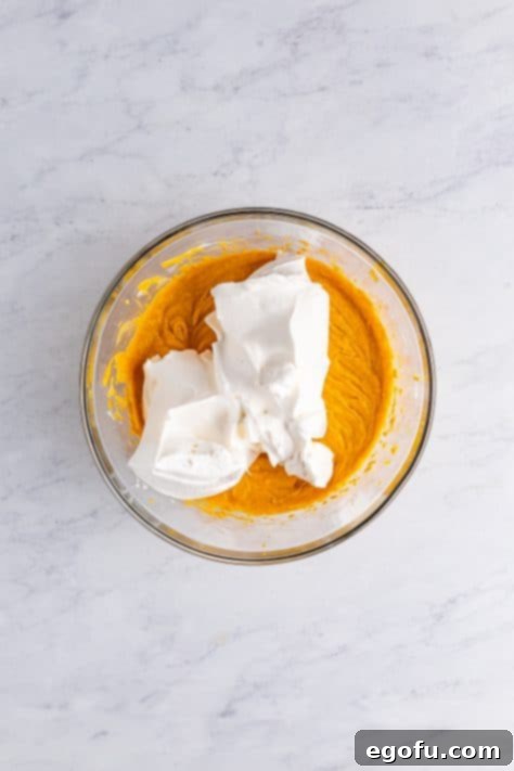 Whipped topping being added to pumpkin cheesecake filling.