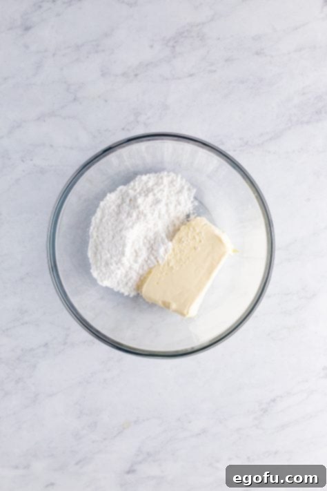 A mixing bowl with powdered sugar and cream cheese.
