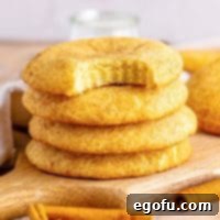 A small stack of Crumbl Snickerdoodles with the top one missing a bite, highlighting their soft texture.