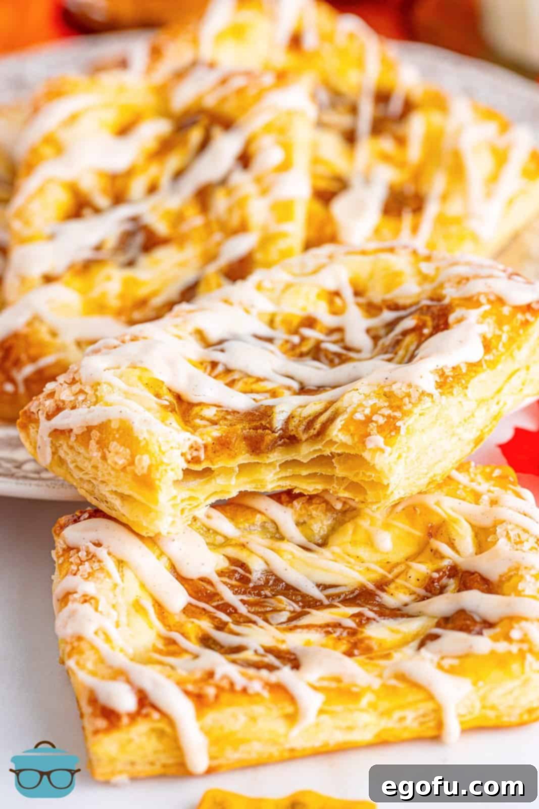 A close-up shot of a pile of Pumpkin Danishes, with one having a bite removed, revealing the delicious filling.