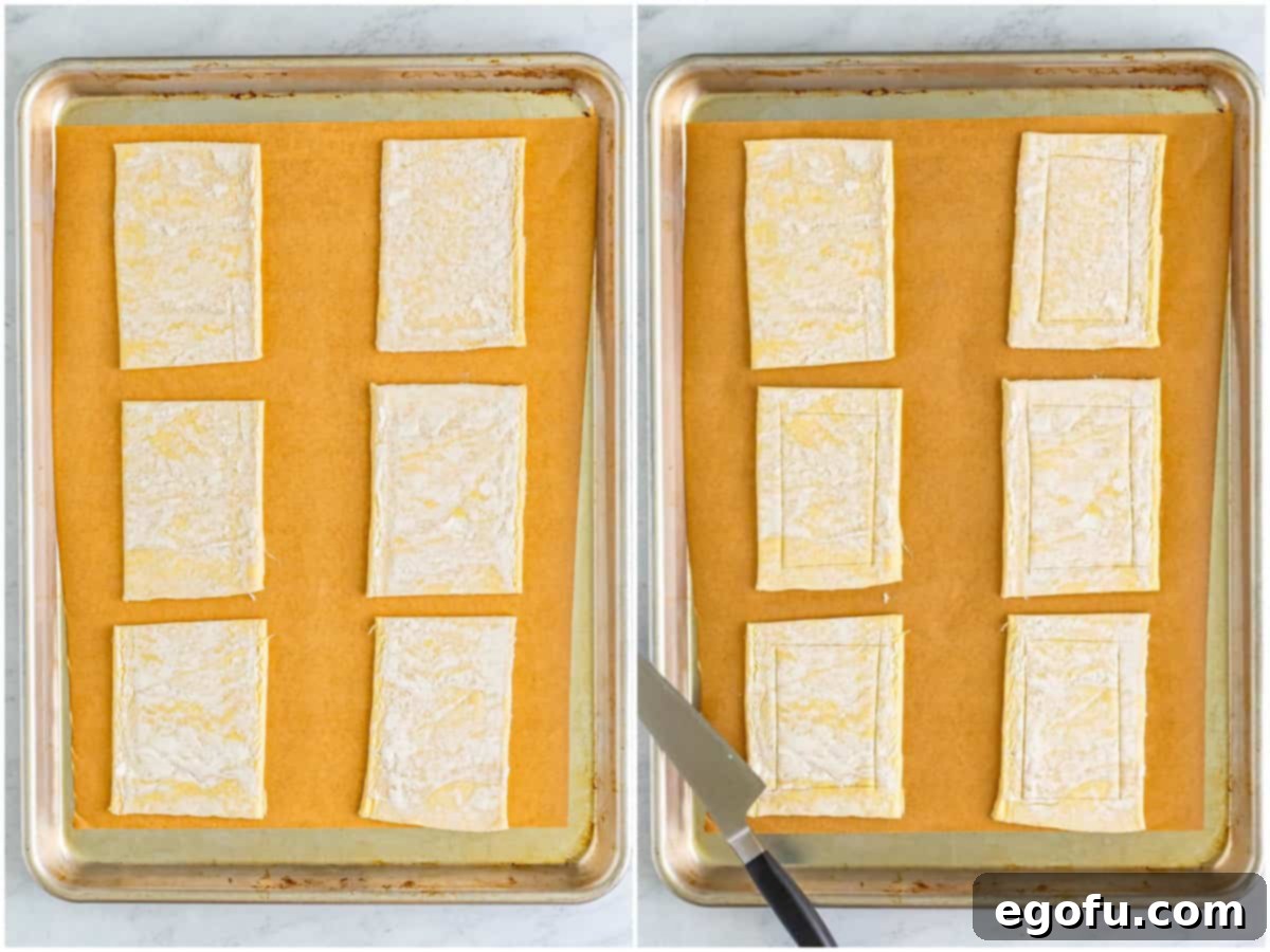 A baking sheet with six puff pastry rectangles, some of which have already been scored along their edges.