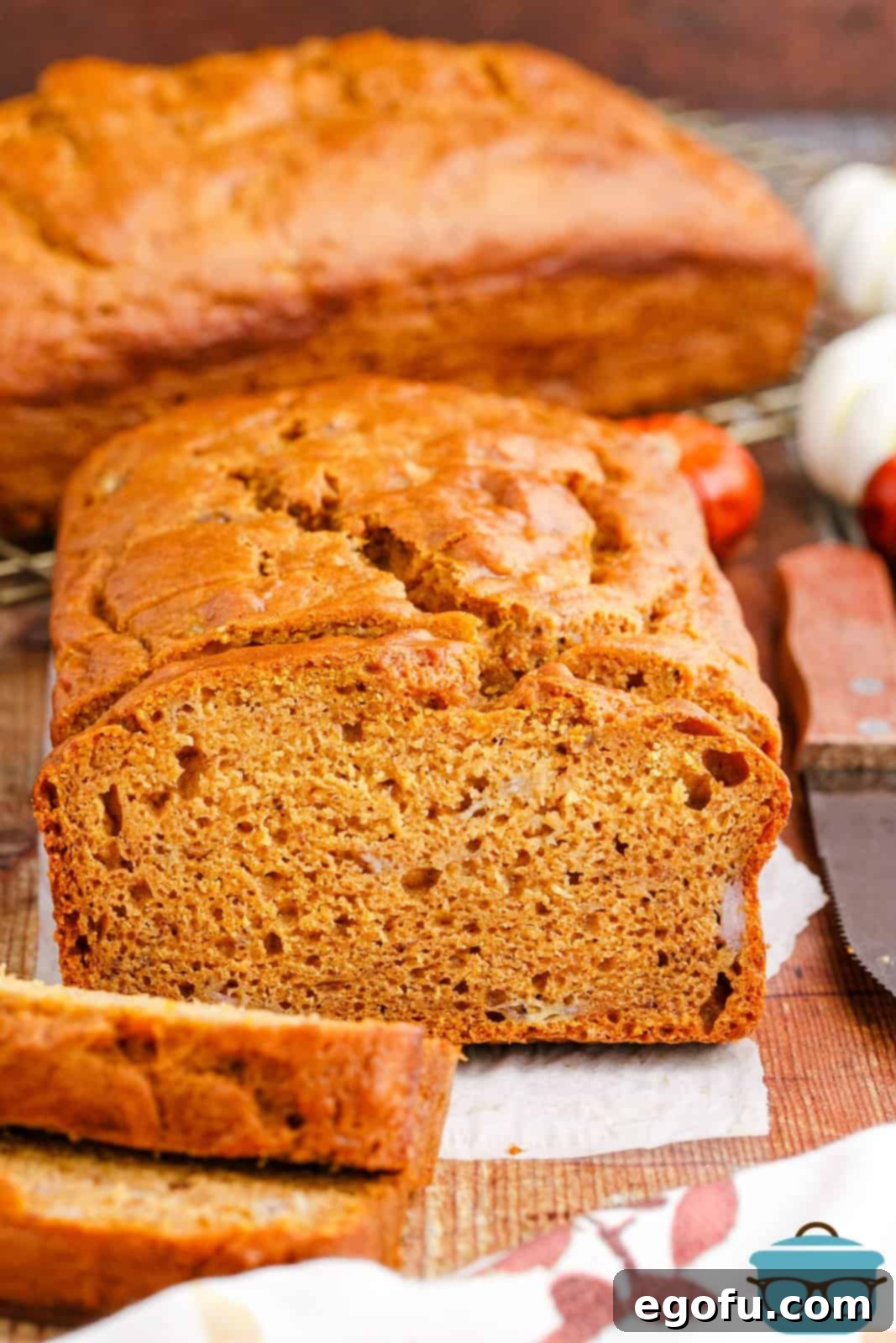 A beautifully baked loaf of Banana Pumpkin Bread with several slices already cut, revealing its moist interior.