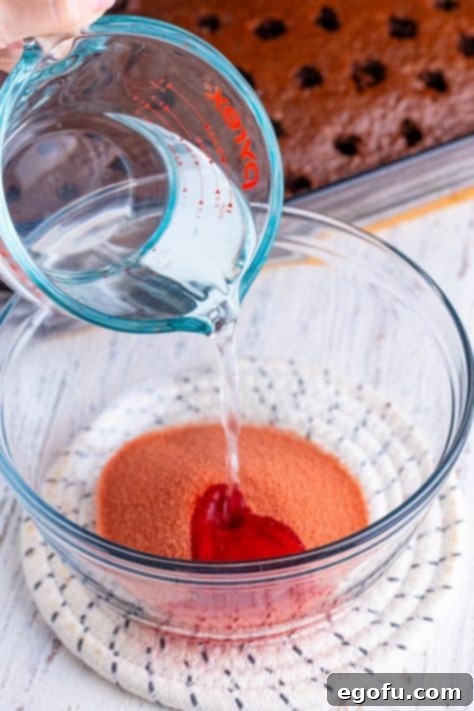 Cherry Jell-O mix with boiling water being poured in.