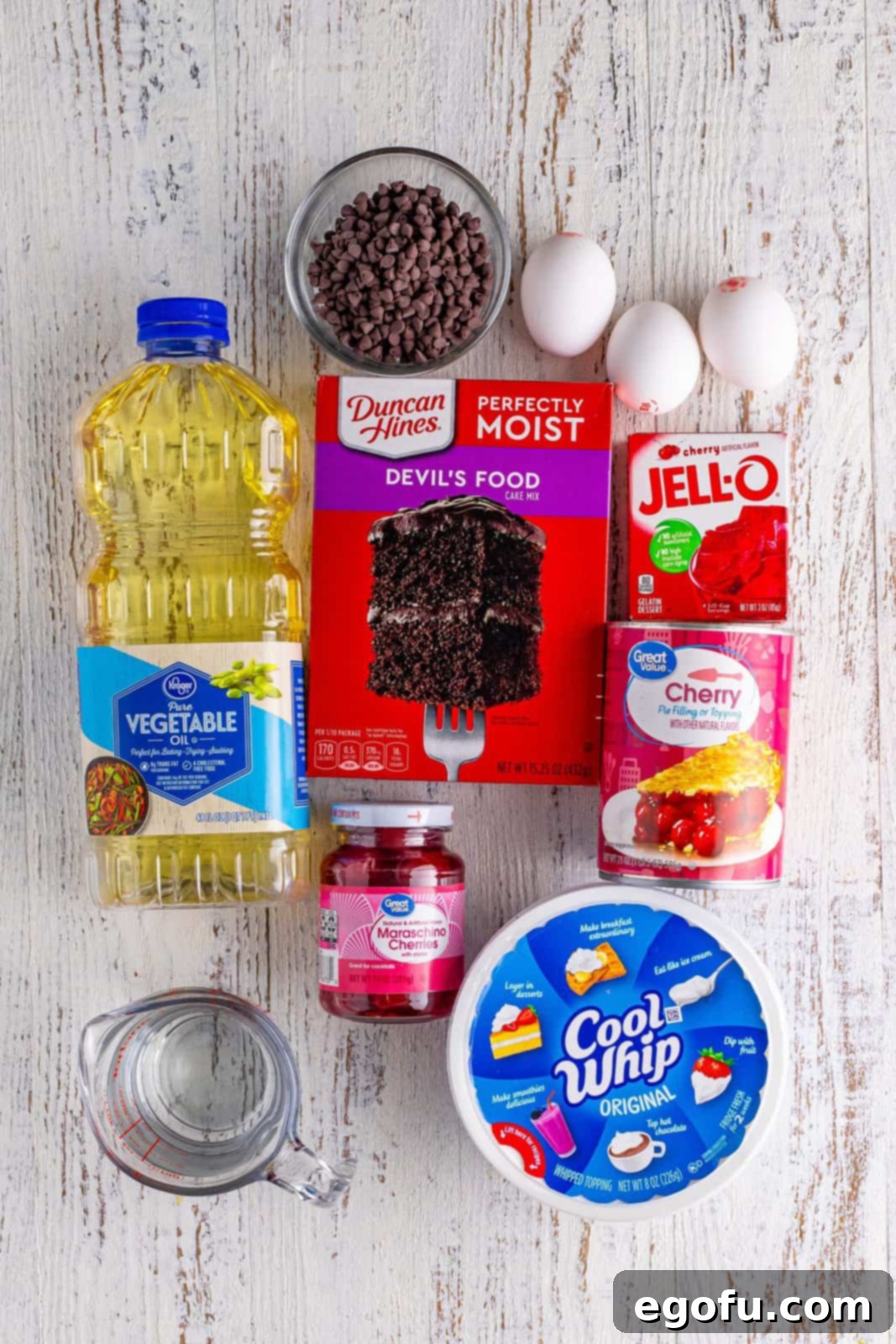 A collage of ingredients for Black Forest Poke Cake: Cool Whip, Devil's Food Cake Mix, vegetable oil, eggs, cherry pie filling, cherry Jell-O, mini chocolate chips, maraschino cherries, and water.