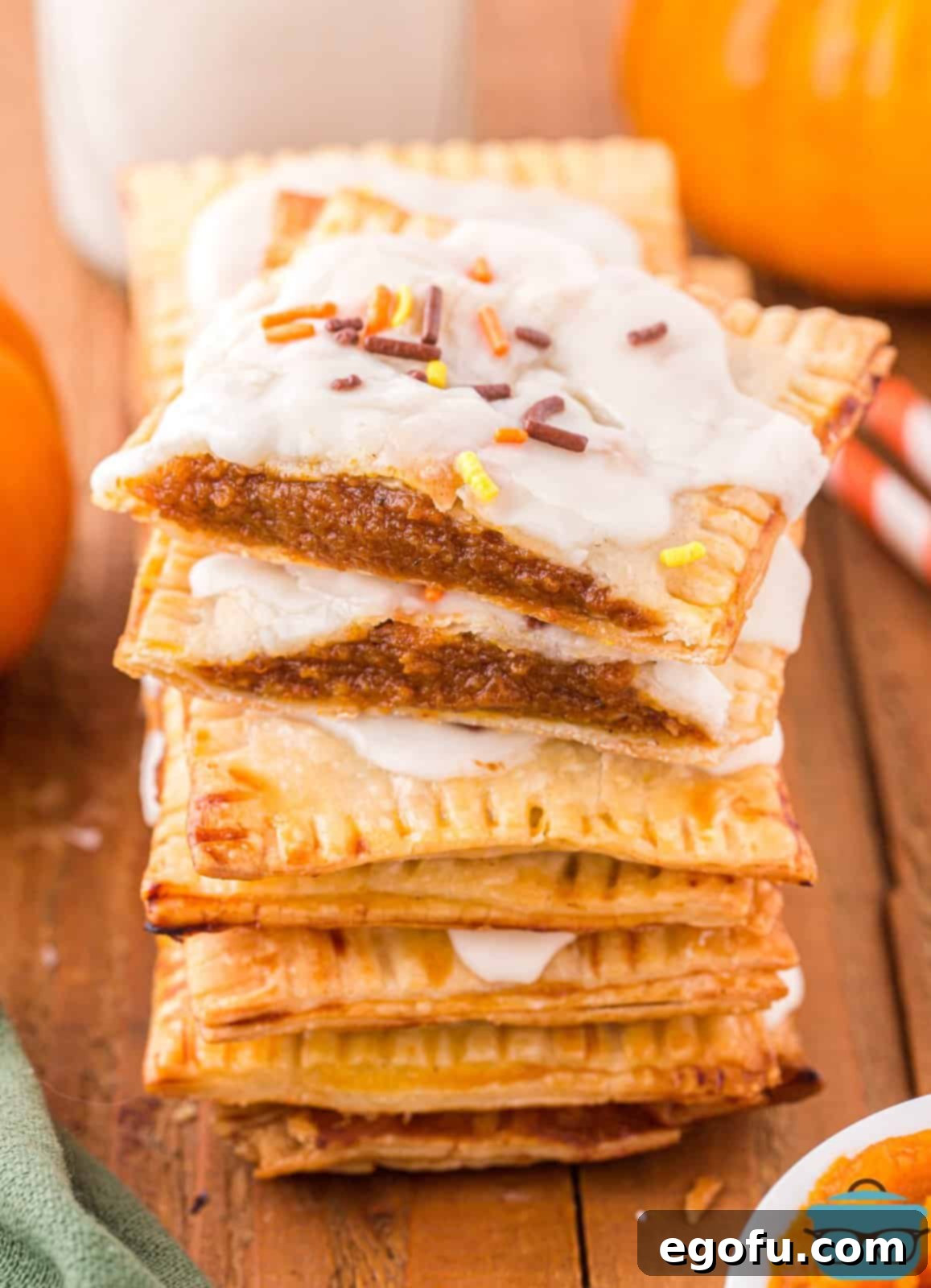 A stack of perfectly baked Homemade Pumpkin Pie Pop Tarts, generously drizzled with sweet maple glaze and adorned with festive autumn sprinkles.