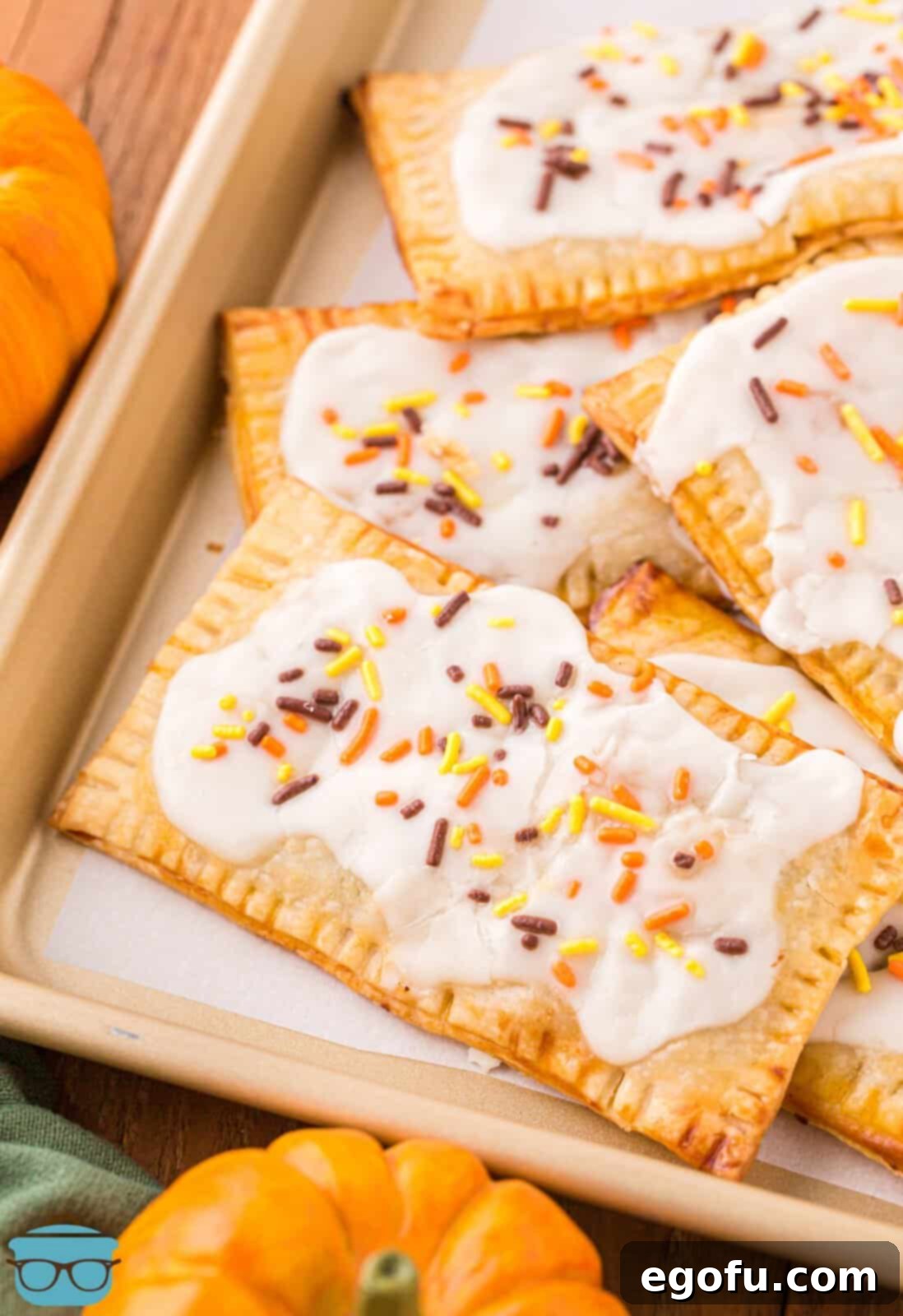 A baking tray filled with beautifully glazed homemade Pumpkin Pop Tarts, generously garnished with colorful fall sprinkles, creating a truly inviting display.
