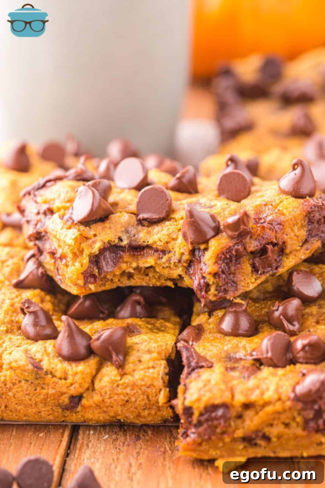 A Chocolate Pumpkin bar missing a bite sitting on top of a few other bars, showcasing its rich, moist interior and melted chocolate chips.