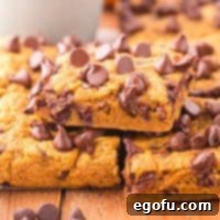 A small stack of homemade Pumpkin Chocolate Chip Bars, showcasing their soft texture and visible chocolate chips.