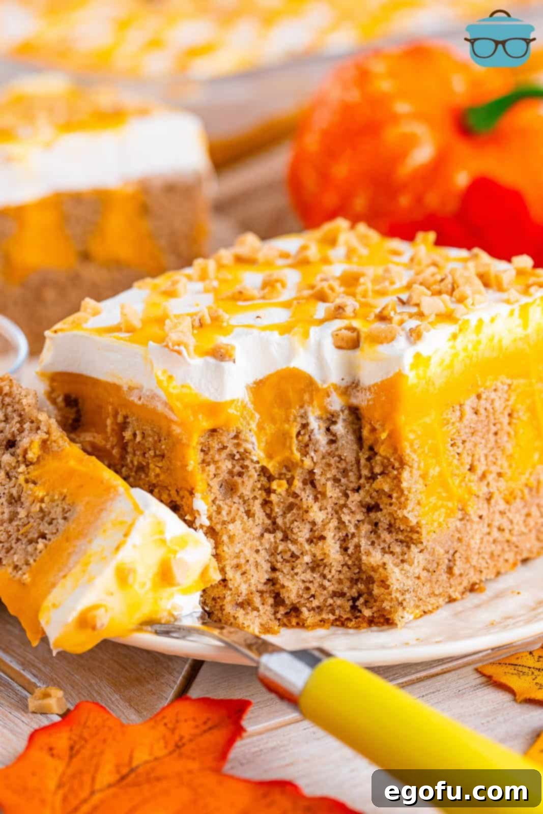 A slice of Pumpkin Poke Cake with a fork and a bite on it.