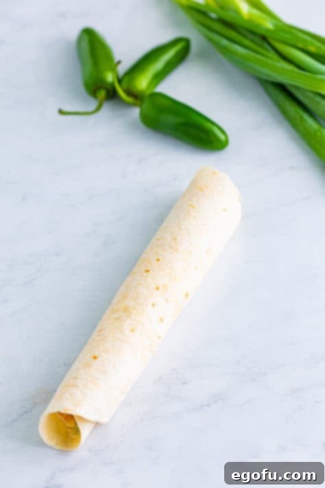 A rolled up tortilla with jalapeno popper filling.