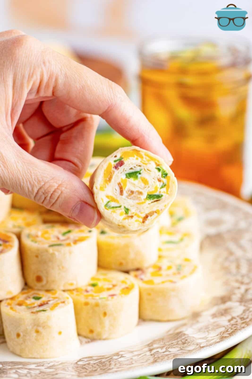 A hand holding a bite sized Jalapeno Popper Pinwheel.