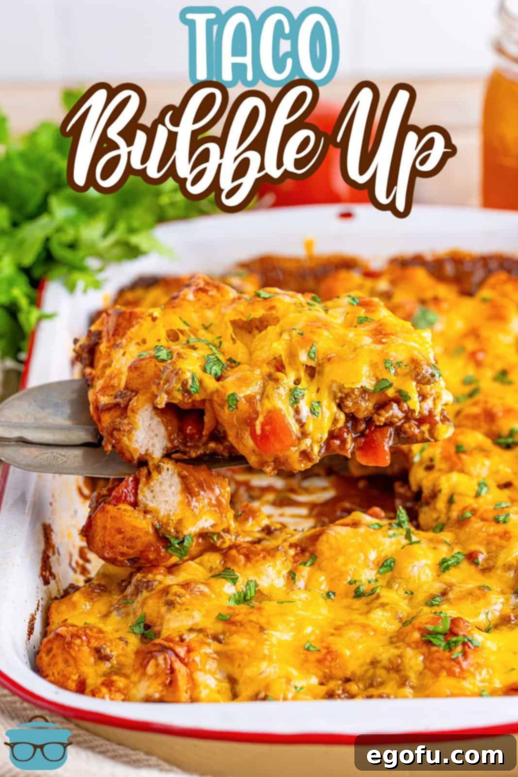 A large serving spoon lifting a portion of cheesy Taco Bubble Up from the baking dish, steam rising enticingly.