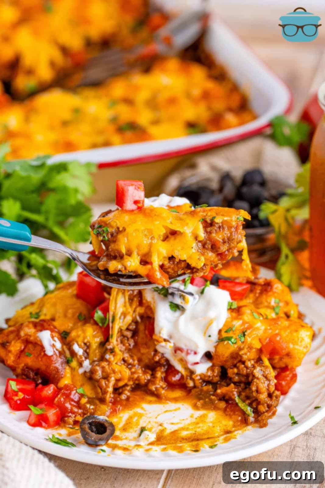 A fork holding a perfect bite of Taco Bubble Up casserole, featuring a piece of fluffy biscuit, seasoned ground beef, and melted cheese, ready to be eaten.