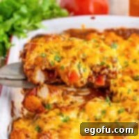 A serving utensil holding some Taco Bubble Up above the baking dish with the rest of it.