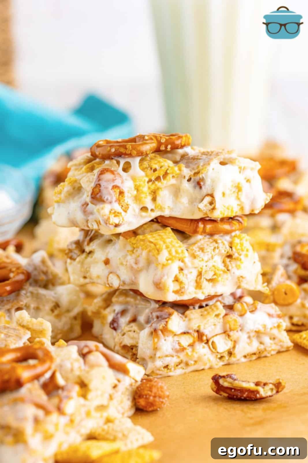 A small stack of Chex Mix Marshmallow Treats, with the top treat having a bite taken out, revealing its soft, chewy interior.