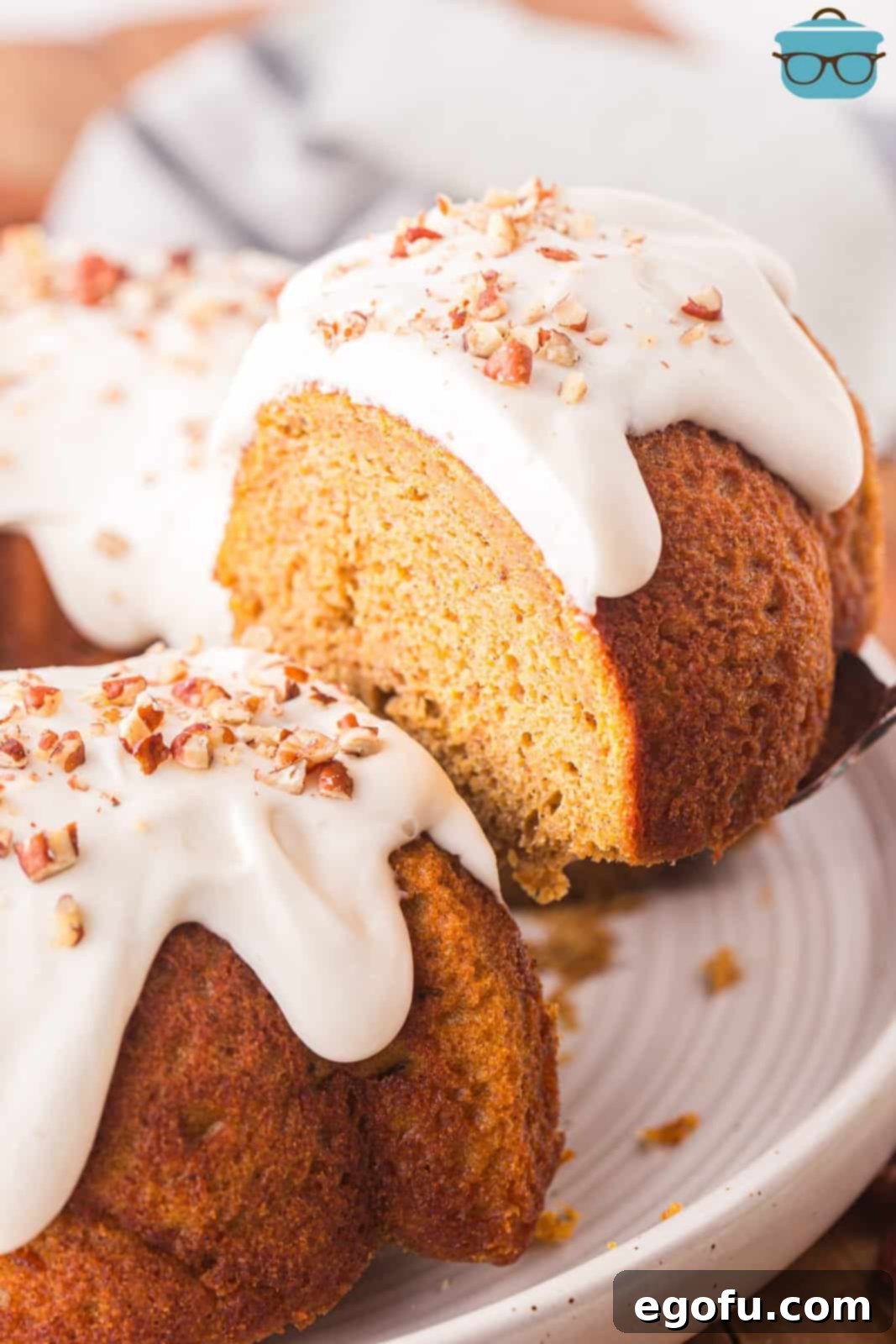 A serving utensil lifting a slice of pumpkin Bundt cake from the rest of the cake.