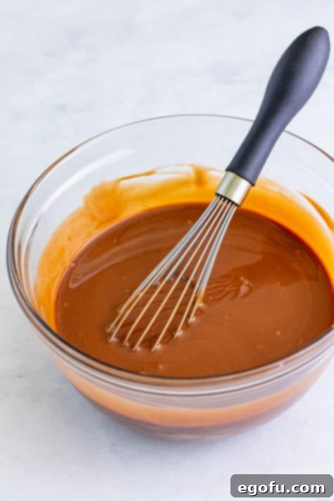 Heavenly Oreo Dream Cake 12 Sweetened condensed milk and chocolate syrup mixed together in a bowl with a whisk.