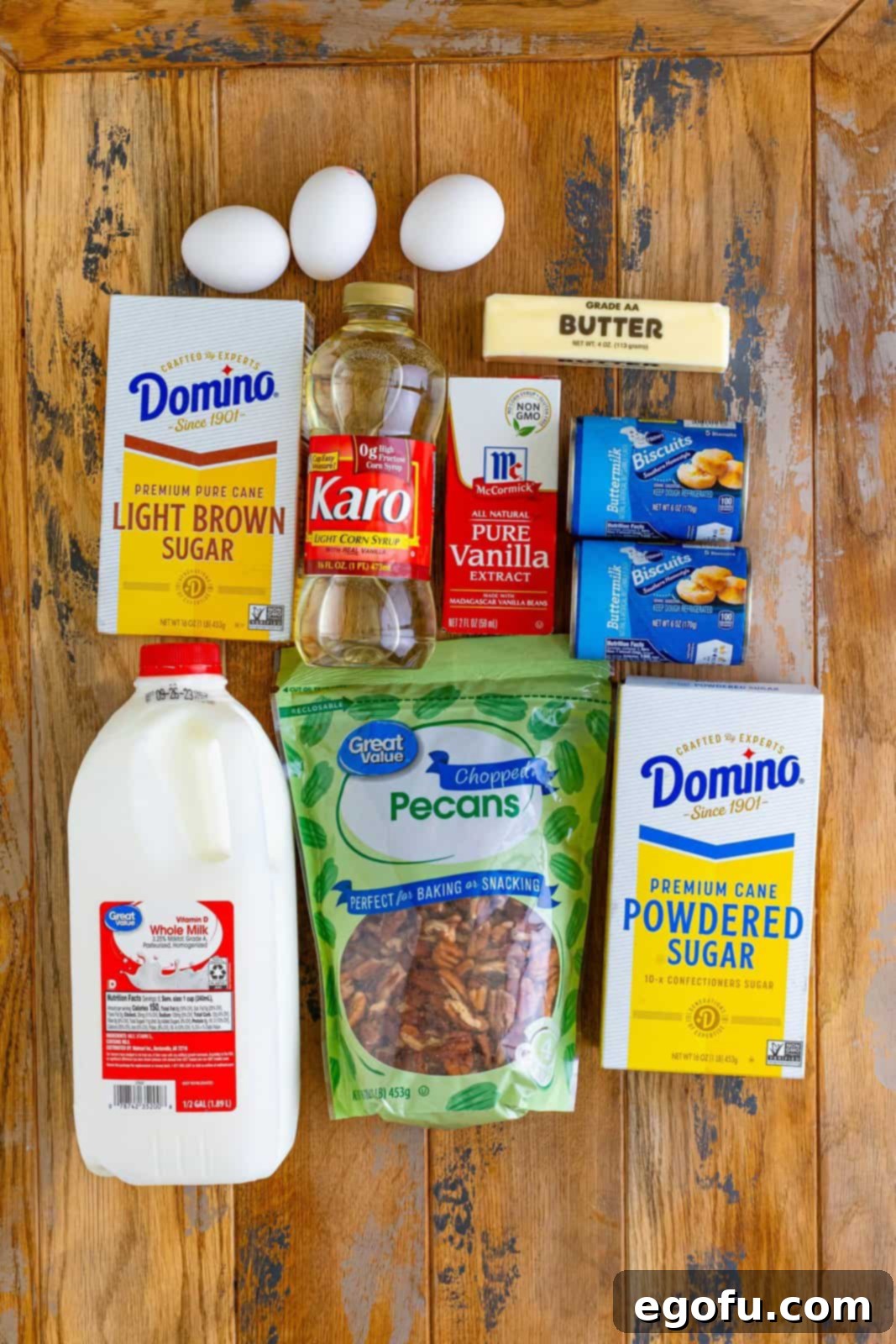 Gooey Pecan Pull-Apart Bake 4 A vibrant collage of ingredients: light corn syrup, eggs, butter, milk, light brown sugar, vanilla extract, canned biscuits, chopped pecans, and powdered sugar, neatly arranged for baking Pecan Pie Bubble Up.