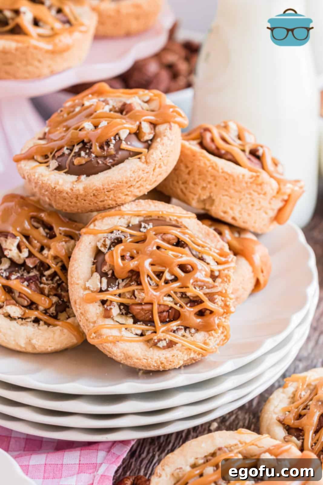 A plate with a pile of Turtle Cookie Cups, showcasing their decadent layers of chocolate, caramel, and pecans on a sugar cookie base.
