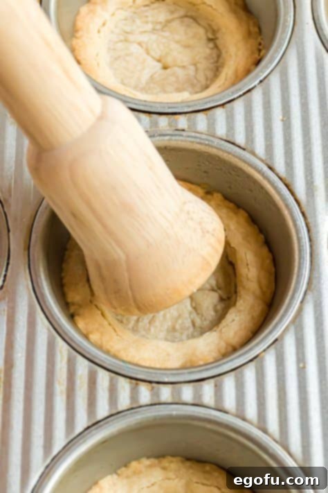 A pestal pushing the center of the cookies down to form a cookie cup.