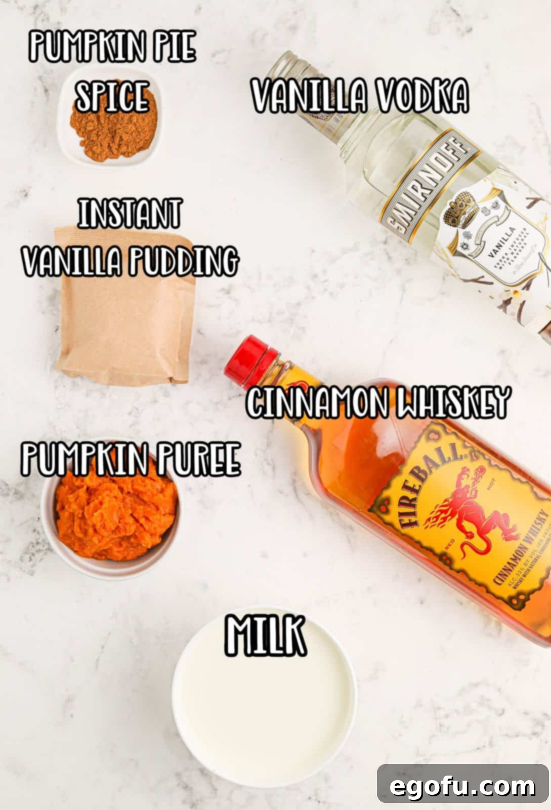 A flat lay photograph showcasing all the key ingredients for Pumpkin Pie Pudding Shots: instant vanilla pudding mix, vanilla vodka, Fireball cinnamon flavored whiskey, milk, pumpkin puree, and pumpkin pie spice, neatly arranged for preparation.