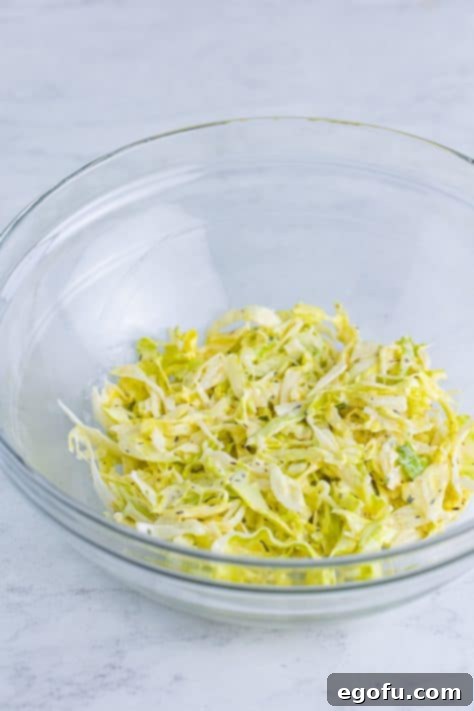 Shredded lettuce in a mixing bowl, generously coated with dressing.