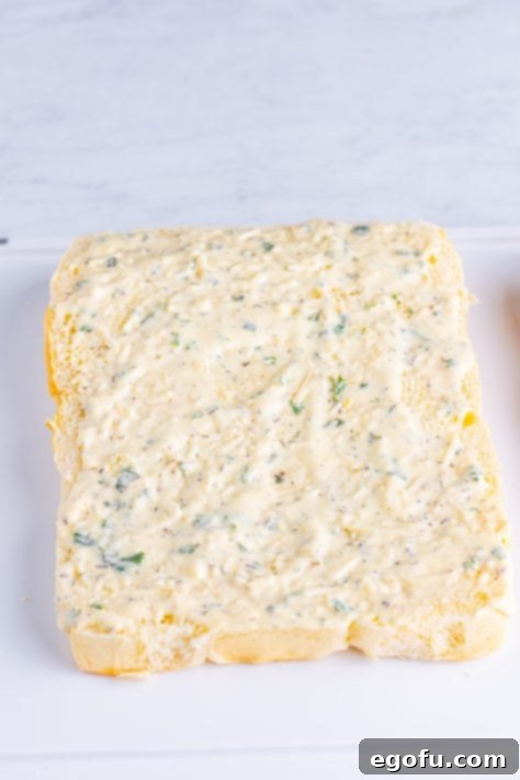 Dressing being spread evenly on a sheet of Hawaiian slider rolls.