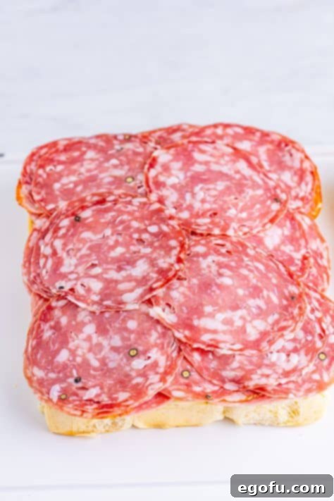 Various deli meats stacked on Hawaiian rolls, ready for additional toppings.