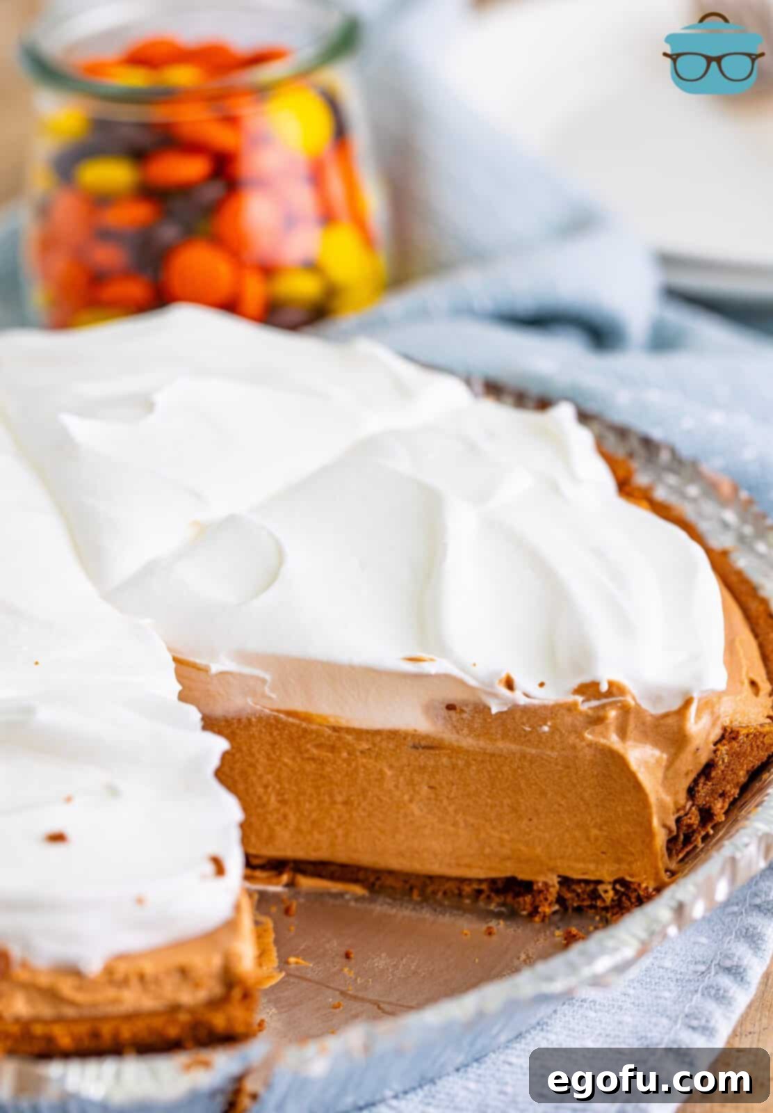 Creamy No Bake Chocolate Peanut Butter Bliss Pie 7 A whole No Bake Chocolate Peanut Butter Pie with a single, inviting slice removed, beautifully revealing its creamy, dual-layered filling, generously topped with fluffy whipped cream.