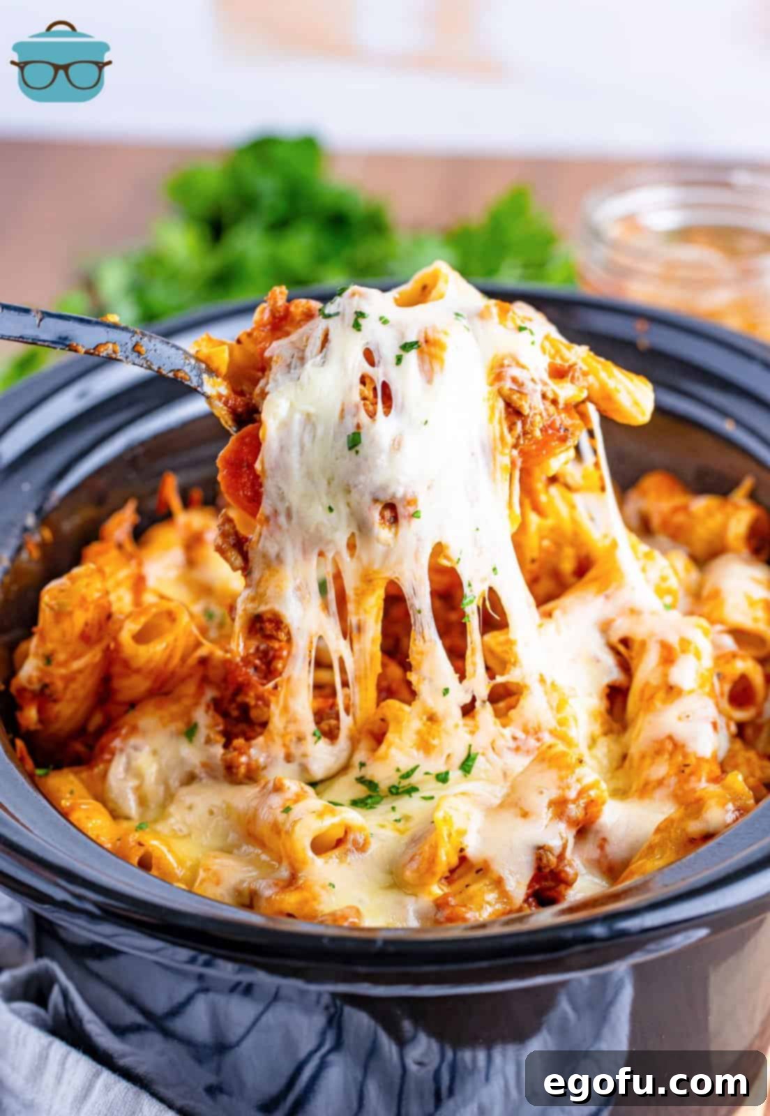 One-Pot Pizza Magic 2 A fork holding a bite of Crock Pot Pizza Casserole, showcasing melted cheese and savory ingredients.