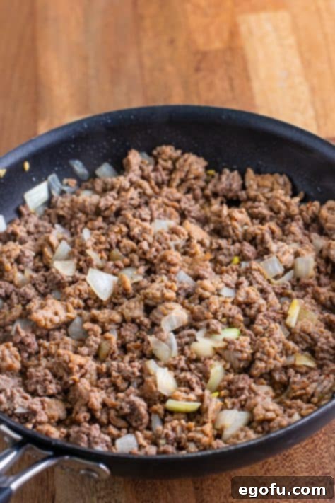 One-Pot Pizza Magic 6 A skillet with onion, ground beef and sausage browning.
