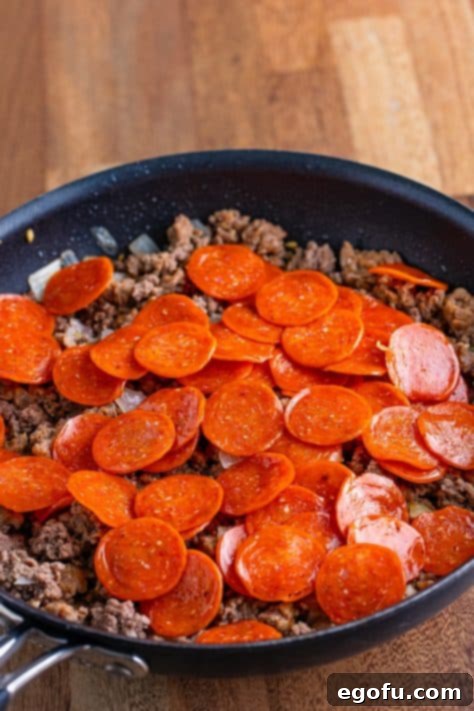 One-Pot Pizza Magic 7 Pepperoni, onion, ground beef and sausage simmering in a skillet.