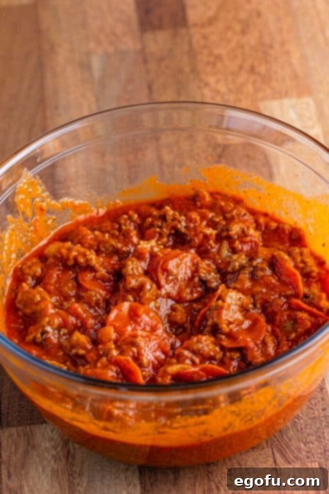 One-Pot Pizza Magic 8 A mixing bowl of pizza sauce, cooked meat, onion, and pepperoni.