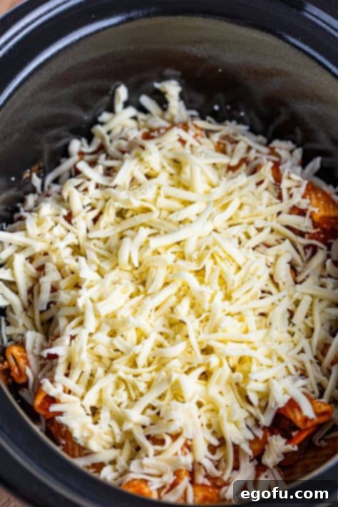 One-Pot Pizza Magic 11 Shredded mozzarella cheese layered on top of the first pasta layer in the slow cooker.