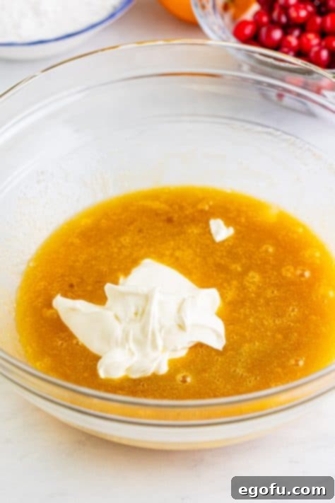 Sour cream, eggs, oil, and brown sugar in a bowl.