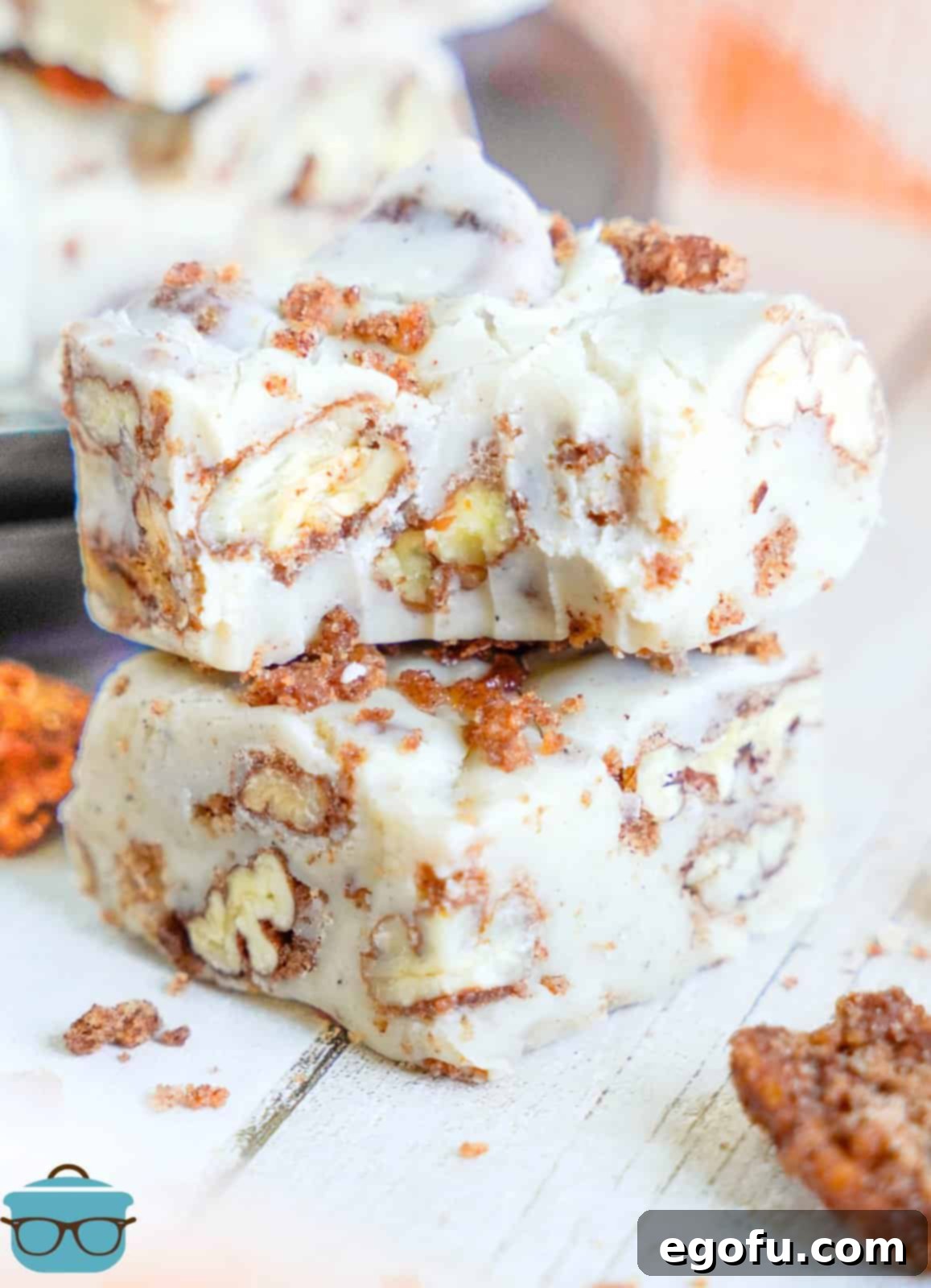 A few pieces of Candied Pecan Fudge, the top piece with a bite missing, showcasing its creamy texture and pecan pieces.